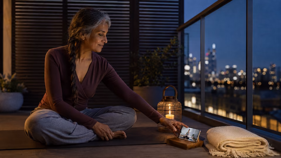 Woman beginning a gentle evening hip mobility yoga class beside a candle and phone